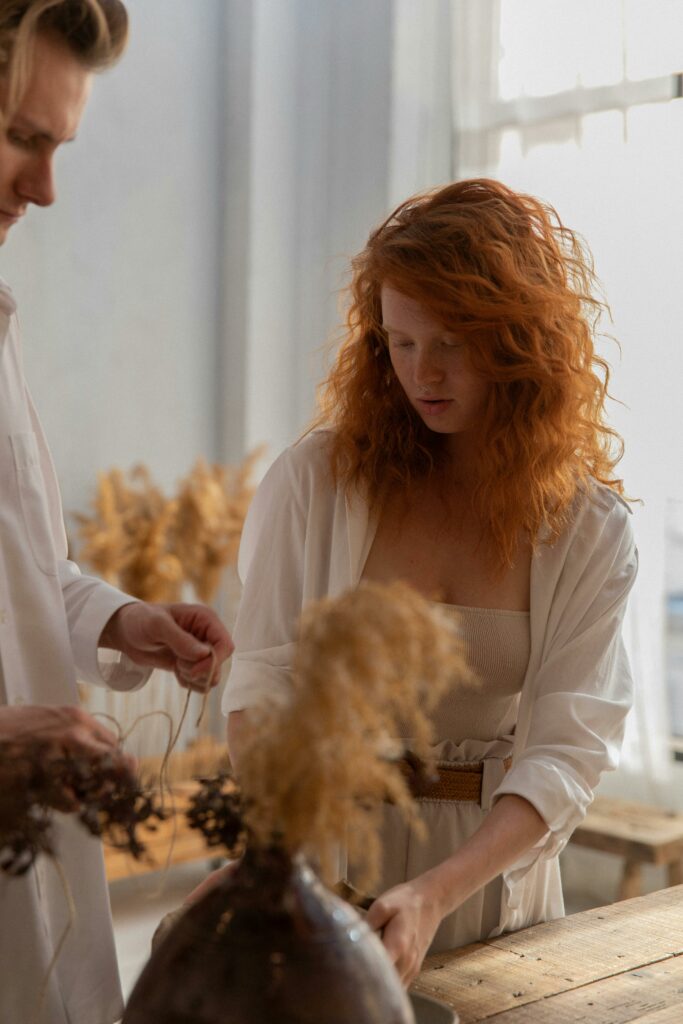 A couple in a peaceful indoor workshop, crafting with natural materials and dried plants.